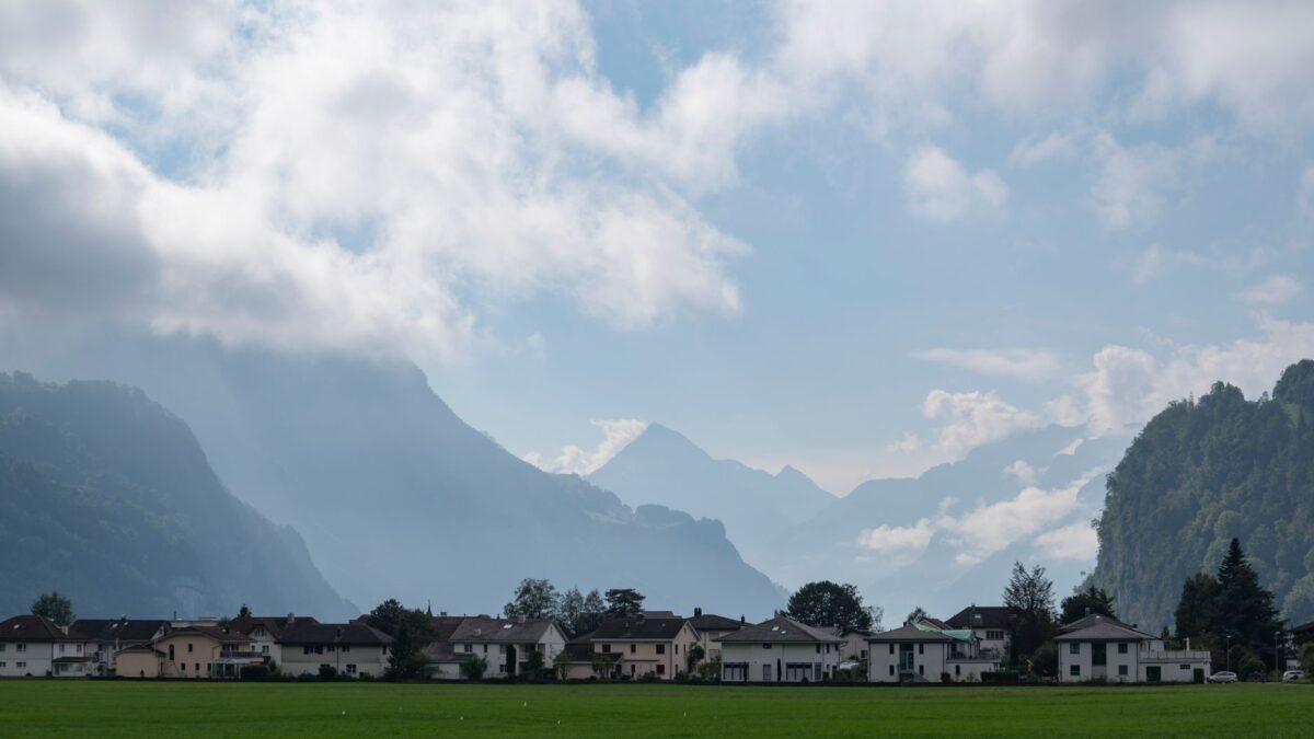 Wohnhäuser in einer Schweizer Gemeinde vor Bergkulisse