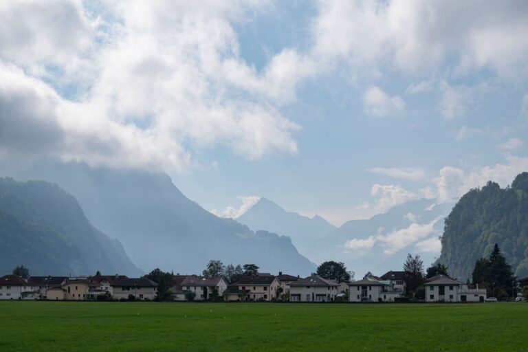 Wohnhäuser in einer Schweizer Gemeinde vor Bergkulisse