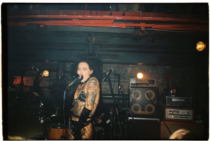 sid vicious - Tattooed female punk singer performing energetically on stage at a concert.