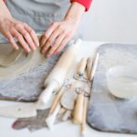 Hände einer Keramikerin an der Töpferscheibe in einer kleinen Werkstatt
