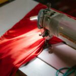 Werktisch mit Nähmaschine, Stoffen und Notizblock in einer kleinen Werkstatt